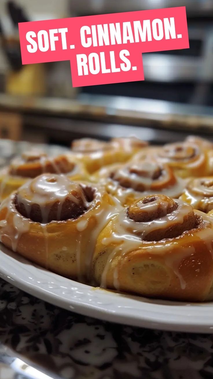 Freshly baked homemade cinnamon rolls with icing on a cooling rack.